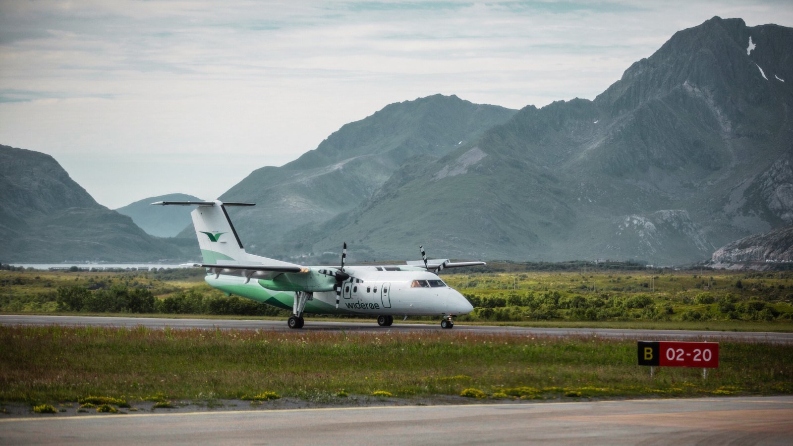 A Widerøe Airlines Dash-8 Q400 turboprop airplane on the apron of Leknes Airport in the Lofoten Islands of Norway. Photo: fivetonine / Shutterstock.com.