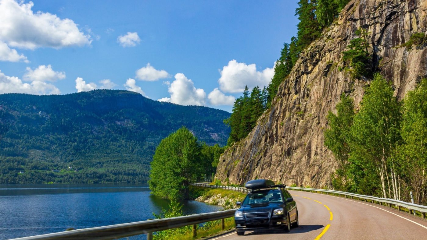 Car on a road skirting a Norwegian fjord.