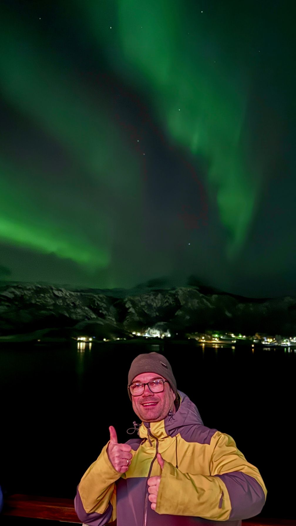David on a northern lights cruise standing in front of a vibrant aurora display. Photo: David Nikel.