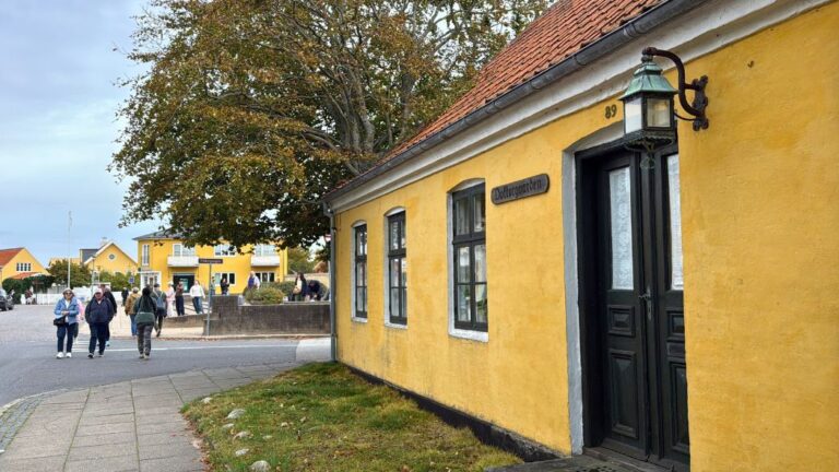 Tourists walk past a yellow house in Skagen, Denmark. Photo: David Nikel.